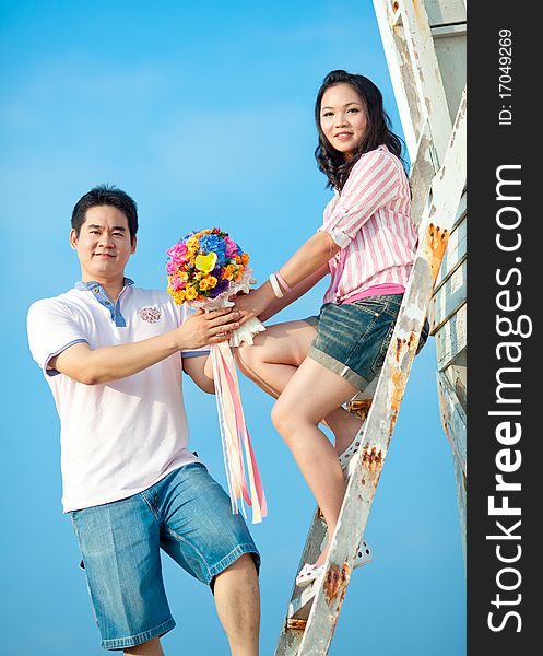 Couple holding beautiful flowers bouquet together on the beach