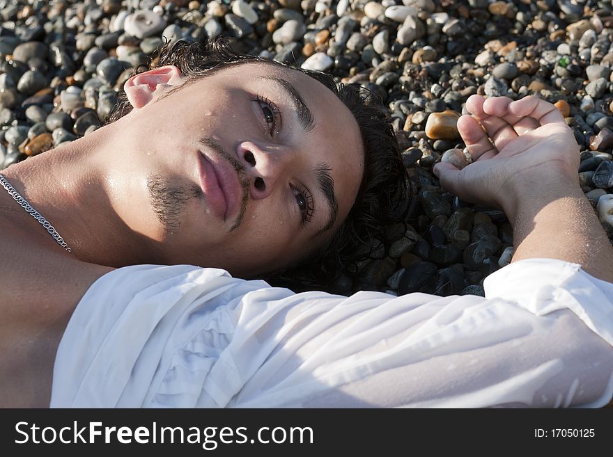 Young man lies on seacoast on pebble