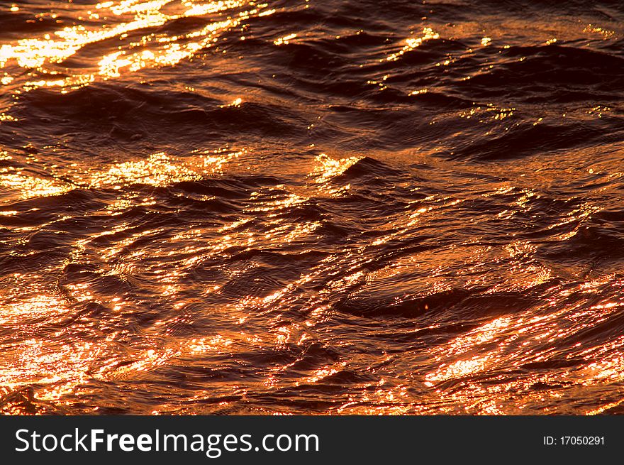Golden sea waves sparkling at sunset