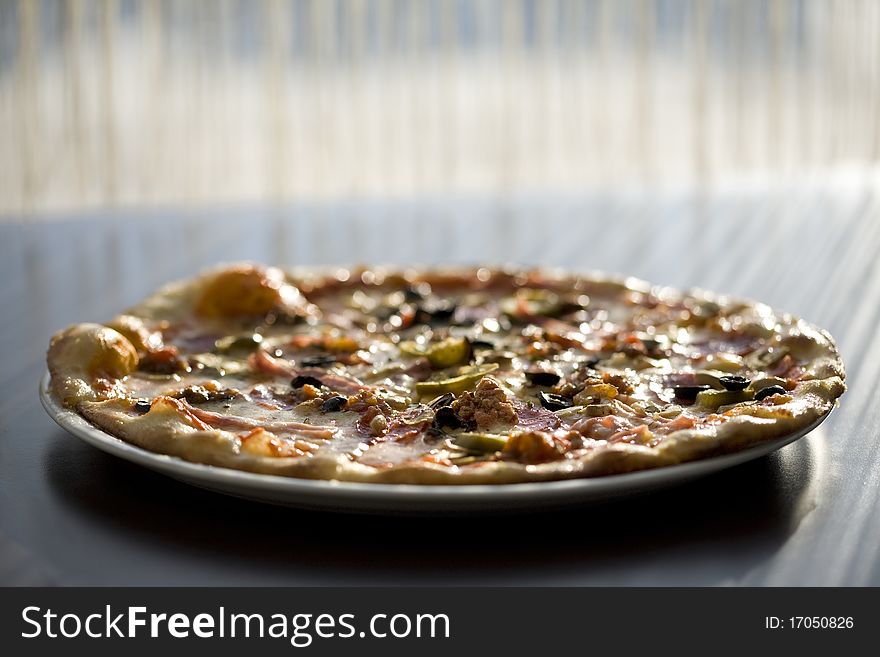 Pizza againts rays of sun on the table shallow focus. Pizza againts rays of sun on the table shallow focus