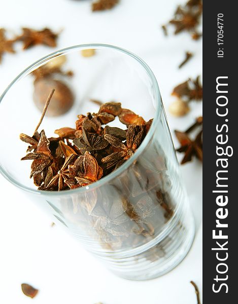 A glass full of anises to be used in spicy cooking with other spices in background. A glass full of anises to be used in spicy cooking with other spices in background.