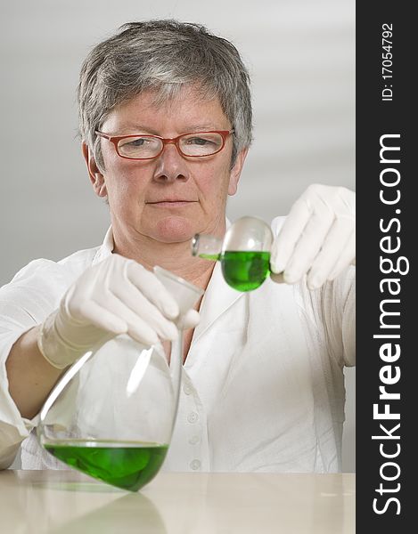Scientist is working with a green liquid on white