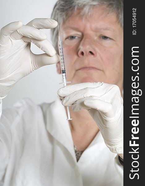 Female doctor preparing for injection on white