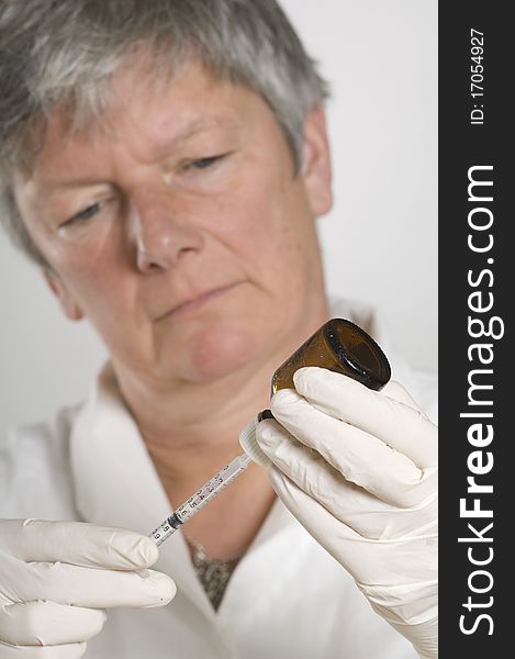 Female doctor holding needle and bottle with medicine