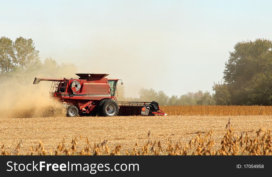 Red combine harvesting a crop of soybeans. Red combine harvesting a crop of soybeans