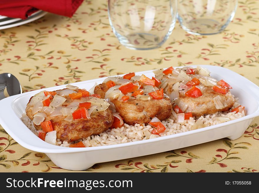 Pork cutlet meal topped with red peppers and onions with rice on a platter