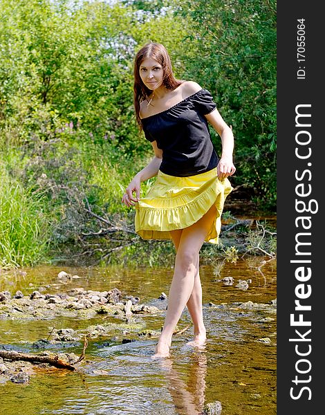 Young woman crossing little stream in forest. Young woman crossing little stream in forest