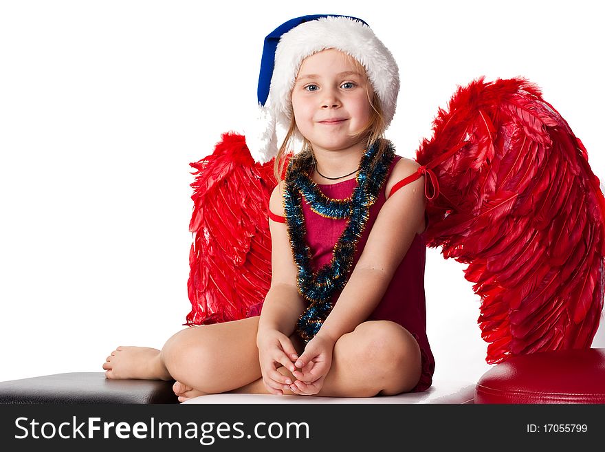 Girl in Santa'sblue hat and tinsel with red angel's wings isolated on white. Girl in Santa'sblue hat and tinsel with red angel's wings isolated on white