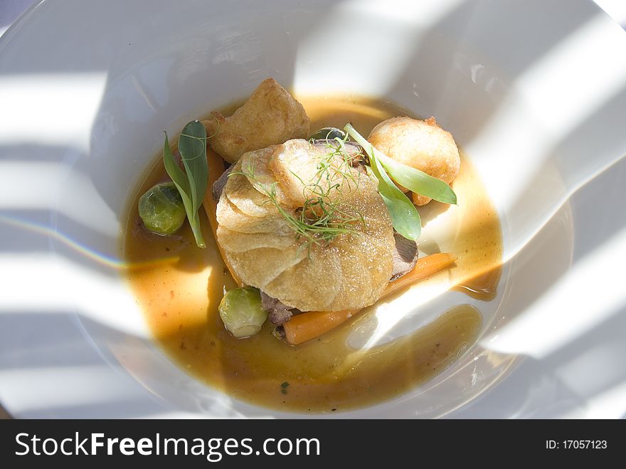 Gourmet dish on white plate and some sun spots.