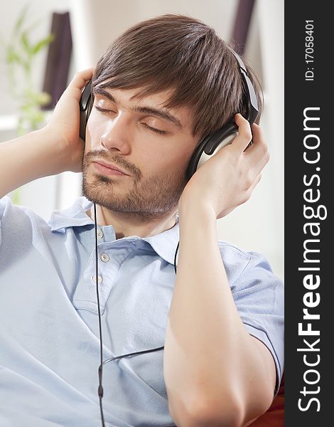 Young man listening music in earphones at home