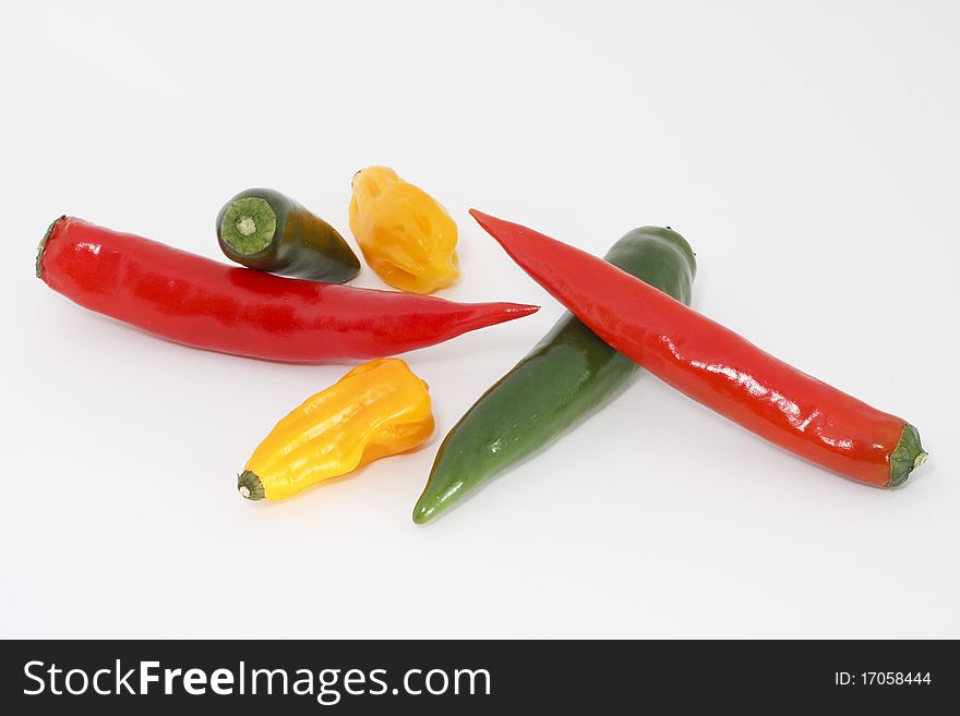 Studio shot, colored chili peppers in front of white background