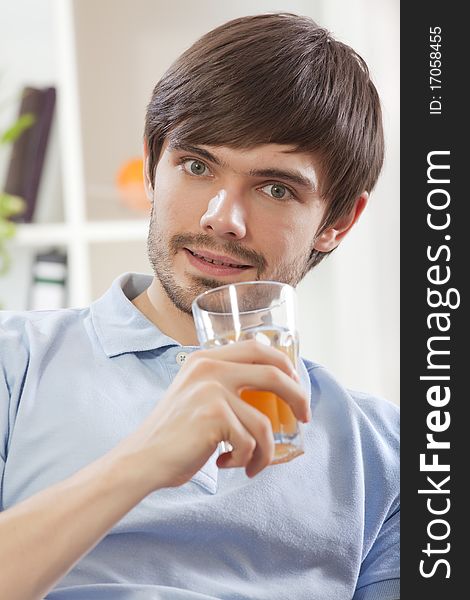 Young man holding glass juice on the sofa at home. Young man holding glass juice on the sofa at home
