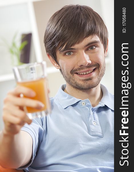 Happy man holding glass orange juice in his hand at home. Happy man holding glass orange juice in his hand at home
