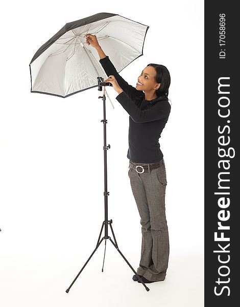 Pretty female photographic assistant adjusting photographic umbrella in studio