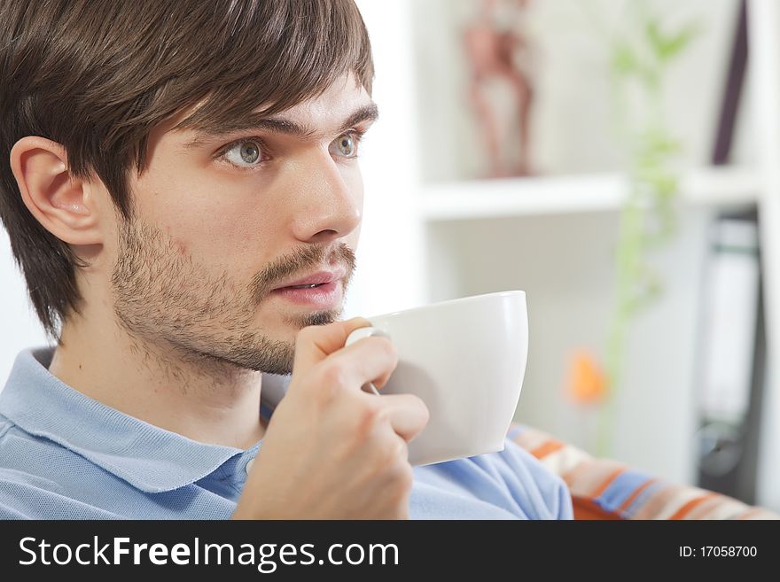 Young man drinking tea while watching television at home. Young man drinking tea while watching television at home