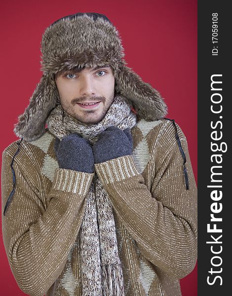 Portrait of happy man in fur hat, gloves and knit scarf over red background. Portrait of happy man in fur hat, gloves and knit scarf over red background