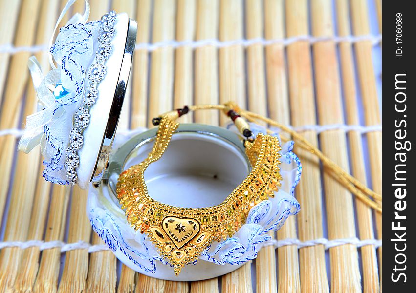 Golden jewellery with jewellery box on wooden background.