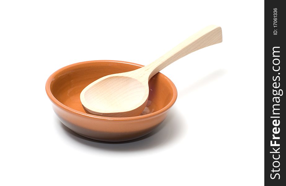 Wooden spoon in a brown ceramic plate. Wooden spoon in a brown ceramic plate.