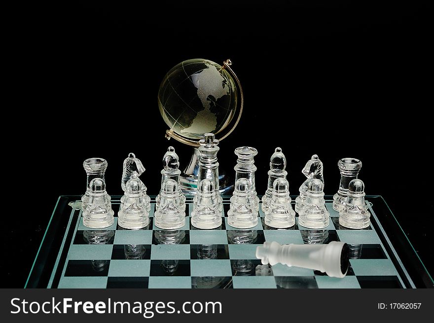 Crystal chess pieces with a globe in the background ana fallen king. Crystal chess pieces with a globe in the background ana fallen king.