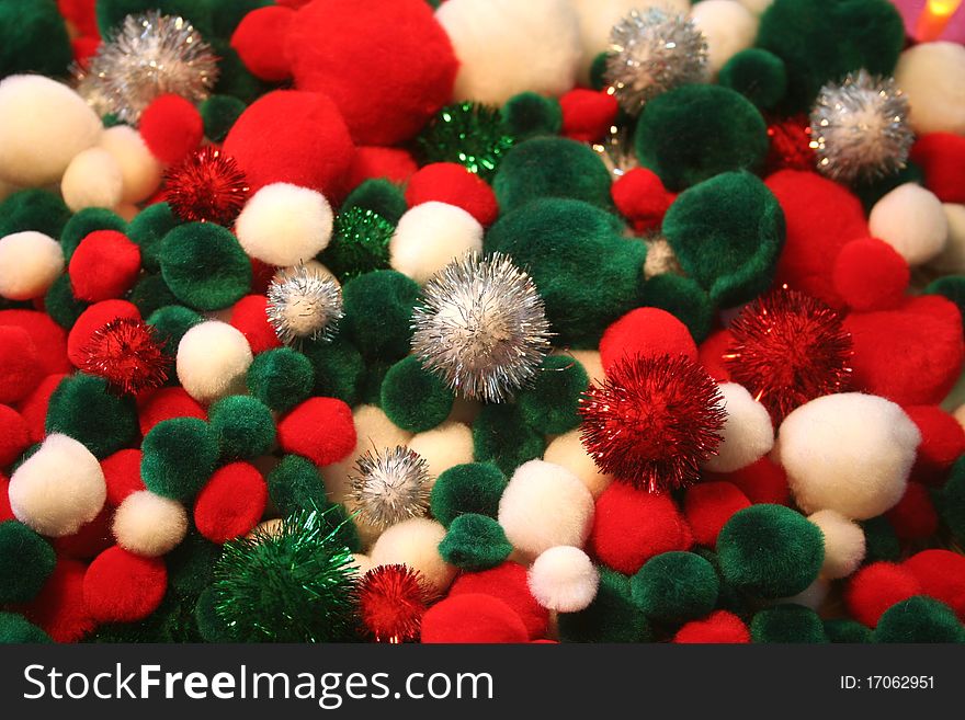 Colorful red, green, and white Christmas pom poms used for crafts with a few sparkly ones.