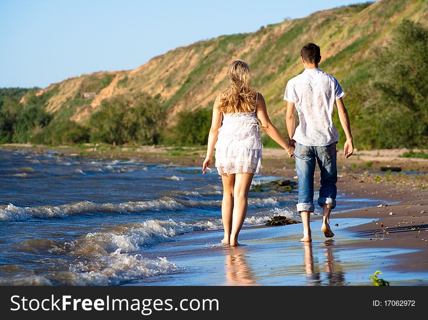 Pair of the enamoured walk ashore having joined hands. Pair of the enamoured walk ashore having joined hands