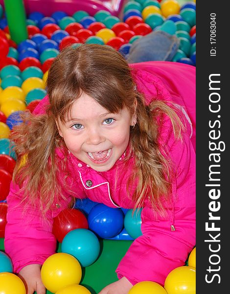 The girl lies on multicolored spheres in a children's attraction