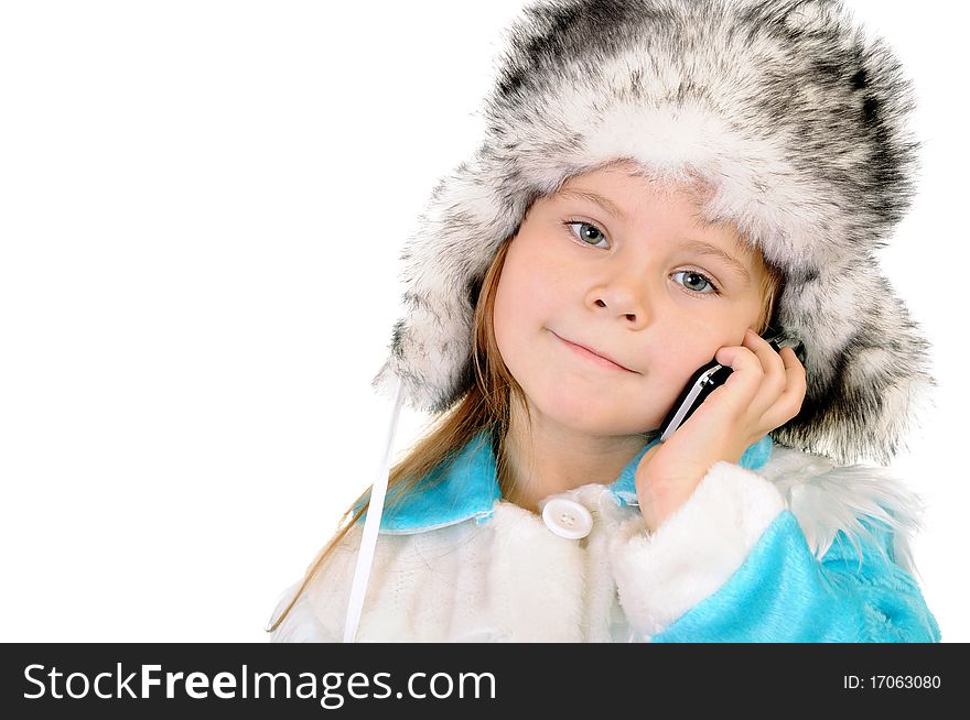 The girl in a winter fur cap speaks by phone on a white background