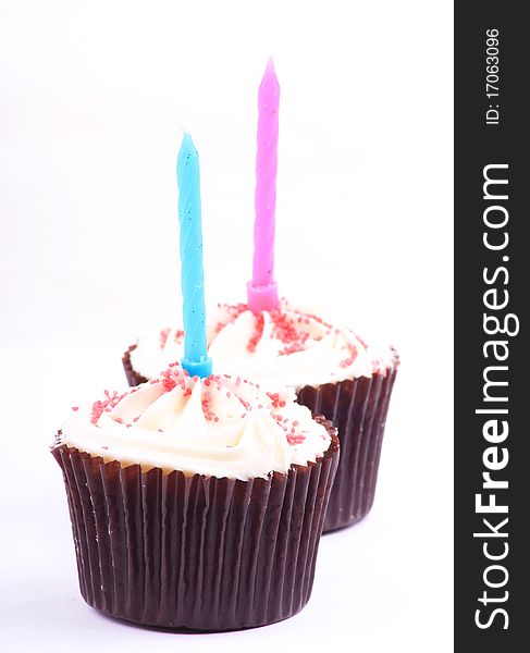 Two lovely looking caked on a white background with a pink and blue candle in them. Two lovely looking caked on a white background with a pink and blue candle in them