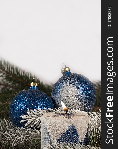 Christmas decoration, blue christmas balls and burning candle on spruce branch