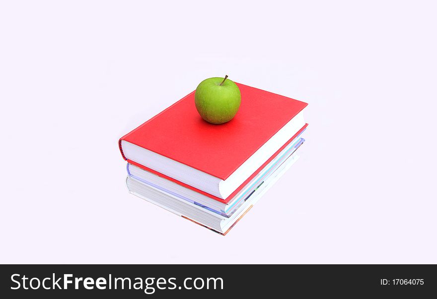 A stack of books with a green apple on top ready for lunch after study. A stack of books with a green apple on top ready for lunch after study