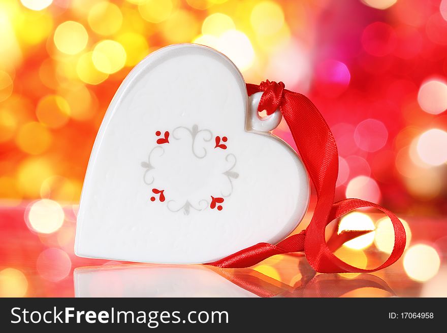 Christmas white heart with red ribbon against blurred background