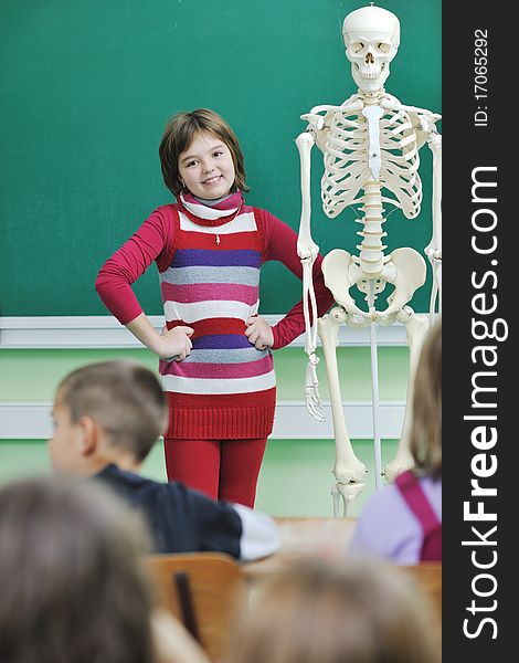 Happy children group in school classrom taking notes and learning biology and anatomy lessons with teacher. Happy children group in school classrom taking notes and learning biology and anatomy lessons with teacher