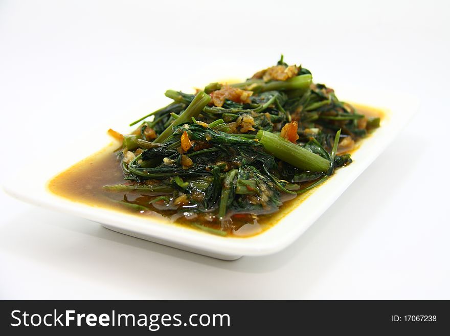 Asian style fried vegetable with shrimps served in white plate with white background.