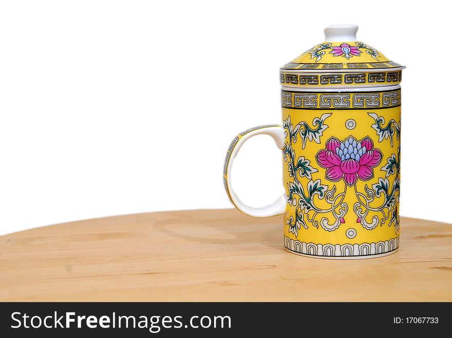 A chinese tea cup with brightly colored floral motif on partial white back ground
