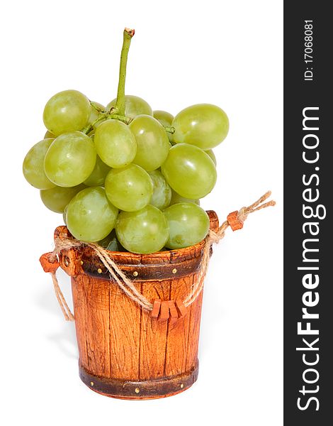 The big cluster of green grapes lies in a small bucket isolated on a white background. The big cluster of green grapes lies in a small bucket isolated on a white background