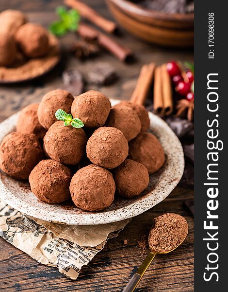 Pile of homemade chocolate truffles rolled in cocoa powder on plate on a wooden table. Tasty sweet dessert. Raw chocolate truffles, vegan chocolate. Pile of homemade chocolate truffles rolled in cocoa powder on plate on a wooden table. Tasty sweet dessert. Raw chocolate truffles, vegan chocolate