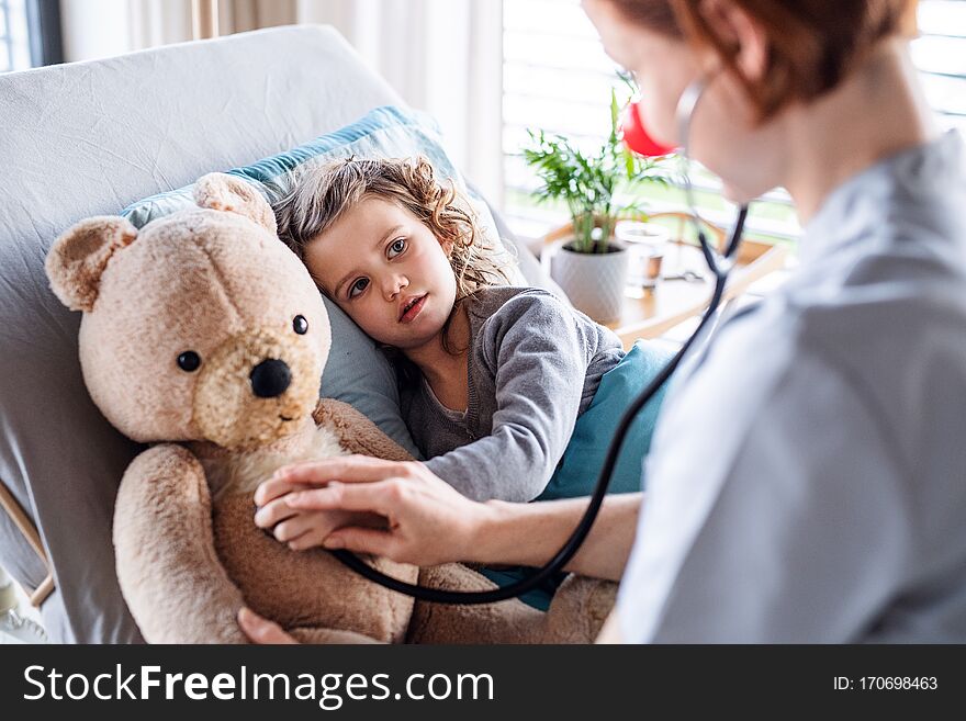 Friendly Female Doctor Examining Small Girl In Bed In Hospital.