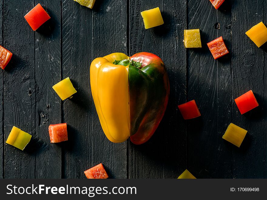 Red And Yellow Raw Peppers Sliced on Black Wooden Surface. Red And Yellow Raw Peppers Sliced on Black Wooden Surface