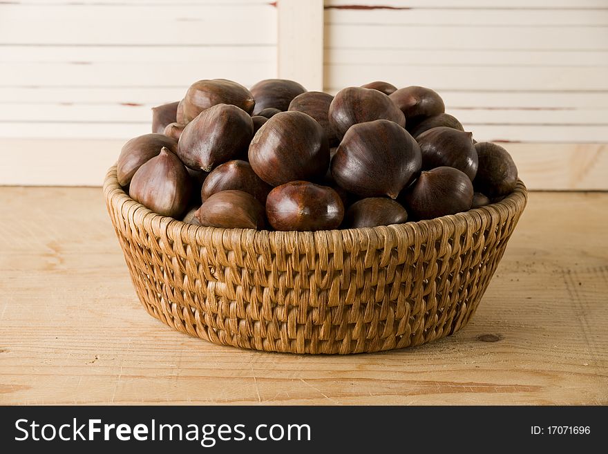 Chestnuts basket isolated on a wooden table, horizontal version