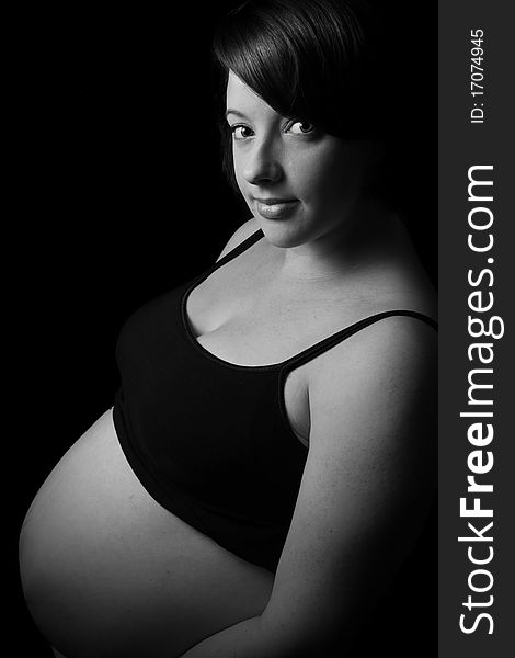Pregnant women with bare belly on black background. Pregnant women with bare belly on black background