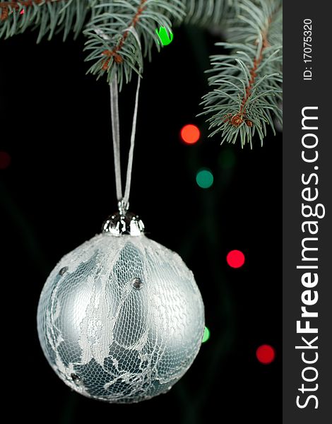 Silver christmas ball on a christmas tree on the black background and colorful light. Silver christmas ball on a christmas tree on the black background and colorful light