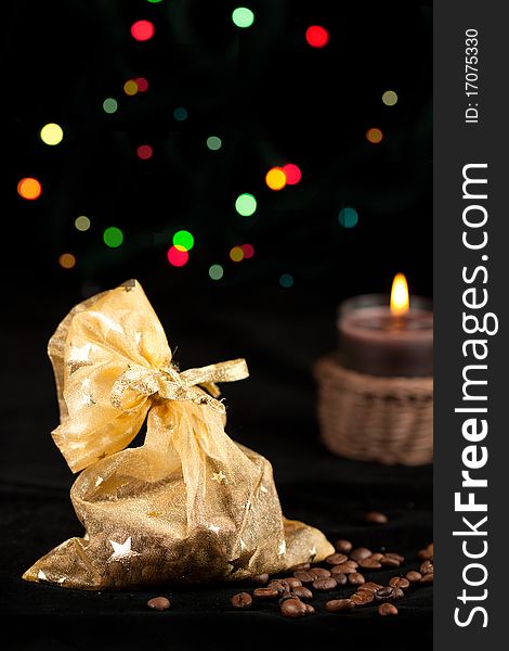 Golden christmas sack with the coffee beans and lightning candle. Golden christmas sack with the coffee beans and lightning candle