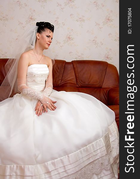 Bride sits on a leather couch.