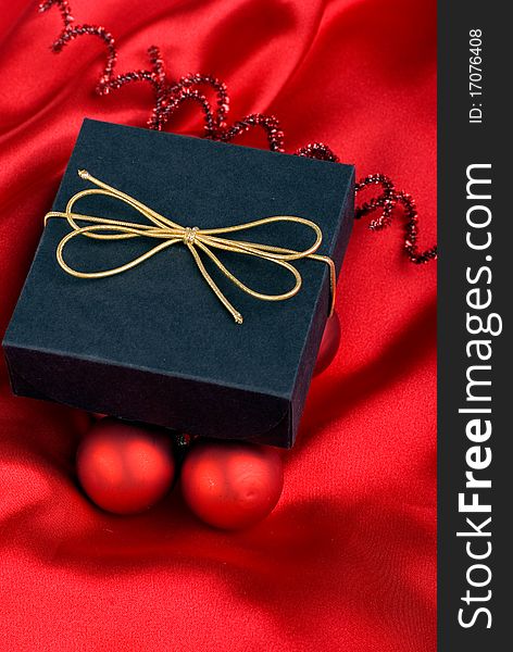 Black gift box with a gold ribbon beside red Christmas balls. Black gift box with a gold ribbon beside red Christmas balls.