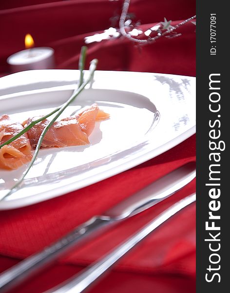 Smoked salmon with chives for Christmas, on a red-decorated table. Smoked salmon with chives for Christmas, on a red-decorated table