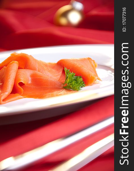 Smoked salmon with parsley for Christmas, on a red-decorated table. Smoked salmon with parsley for Christmas, on a red-decorated table