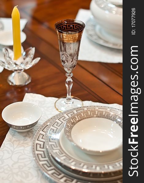 A table decorated with dishes, goblet and candle. A table decorated with dishes, goblet and candle