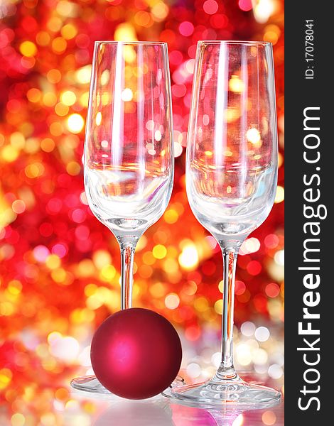 Two empty glasses and red ball decoration for champagne on the blurred background