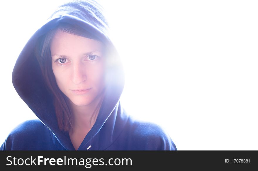 Portrait of a pretty young woman wearing a blue hoodie on glowing background