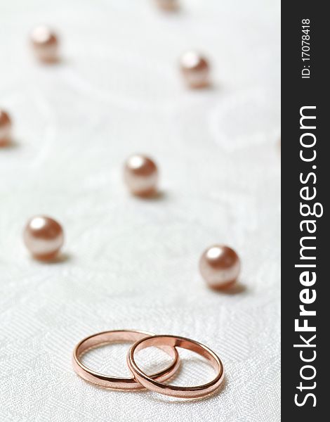 Wedding rings on lace light background with pearls